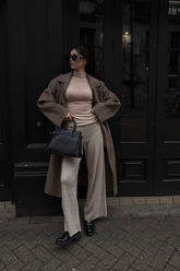a lady wears a camel wrap coat with beige top and pants